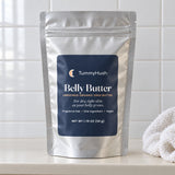 TummyHush Belly Butter pouch on a bathroom shelf beside a washcloth