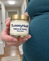 TummyHush Tallow & Honey Belly Balm jar held in a hand