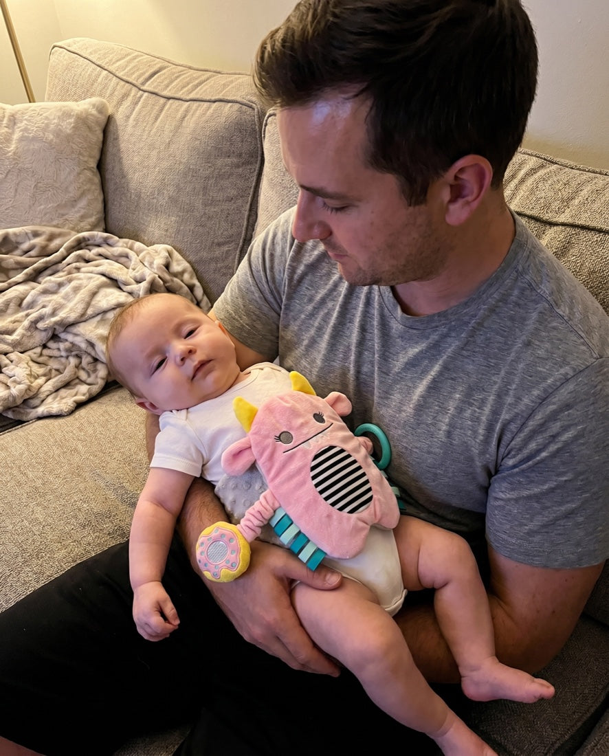 Dad cradling a calm, drowsy baby wearing the Snuggle Monster band