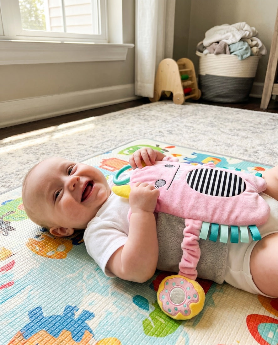Happy baby reaching for the Snuggle Monster's teether ring