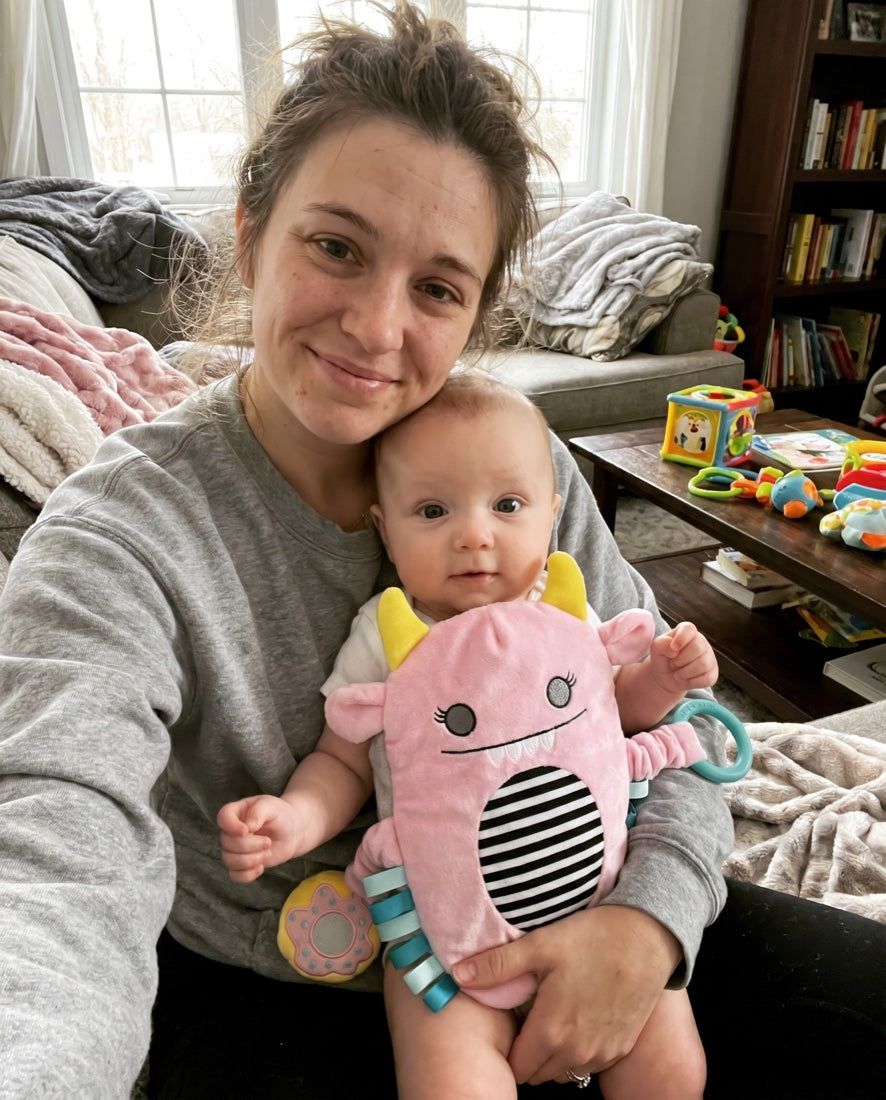 Smiling mother holding her baby who is wearing the Snuggle Monster band