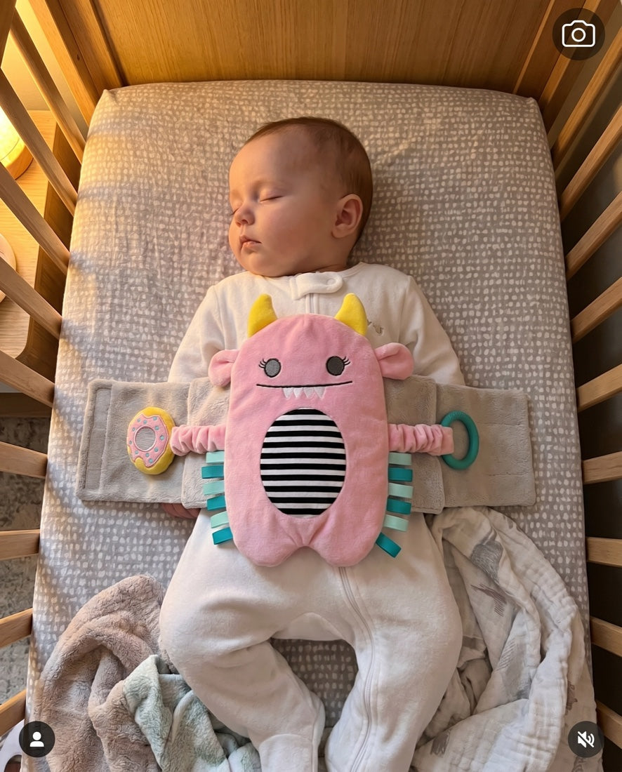 Peaceful sleeping baby in a crib wearing the Snuggle Monster band